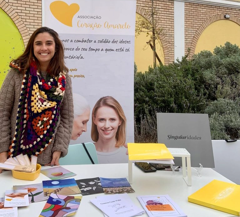 voluntaria numa mesa com pecas de comunicacao sobre a associacao