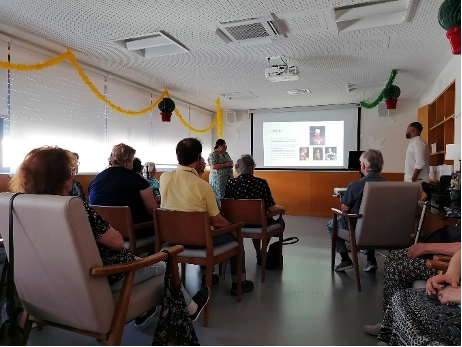 Sala com utentes e um orador a fazer uma apresentacao com projeccao na tela